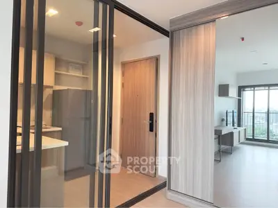 Modern apartment interior with sliding glass doors, open kitchen, and spacious living area with city view.