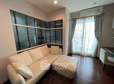 Modern living room with white sofa and large windows, featuring elegant curtains and wooden flooring.