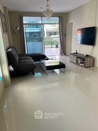 Spacious living room with modern decor and large glass doors leading to a balcony.