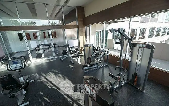 Modern gym with state-of-the-art fitness equipment and large windows for natural light.