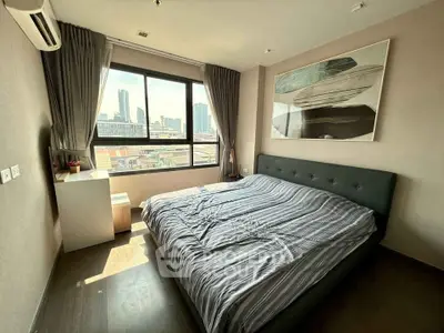 Modern bedroom with city view, featuring a large bed and stylish decor in a high-rise apartment.