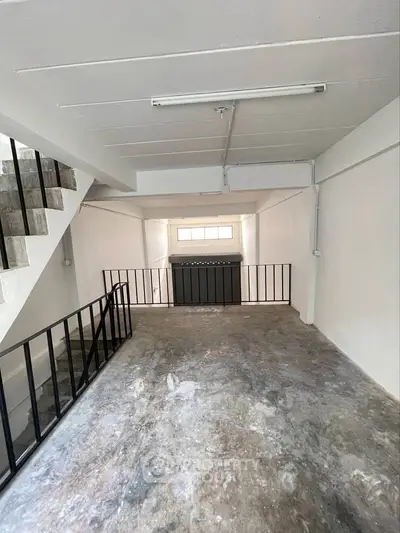 Spacious industrial-style interior with concrete flooring and modern railing.