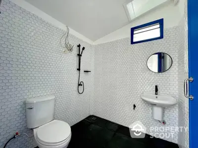 Modern bathroom with hexagonal white tiles, sleek fixtures, and contrasting dark floor, creating a clean and contemporary space.