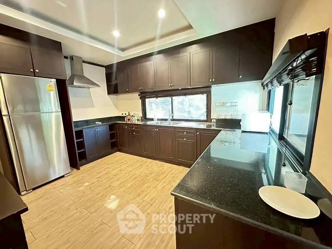 Spacious modern kitchen with dark wood cabinets and stainless steel appliances