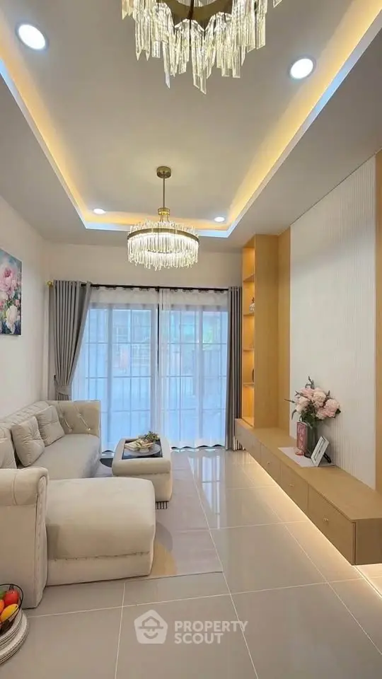 Elegant living room with modern chandelier, plush sofa, and floor-to-ceiling windows for natural light.