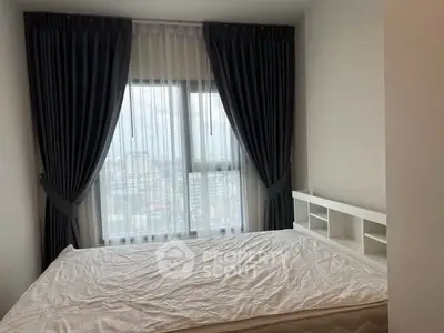 Cozy bedroom with large window and elegant curtains offering city view.