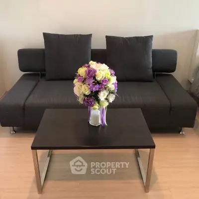 Modern living room with sleek sofa and elegant floral centerpiece on coffee table.