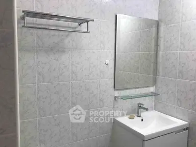 Modern bathroom with sleek sink and mirror, featuring elegant tile design.