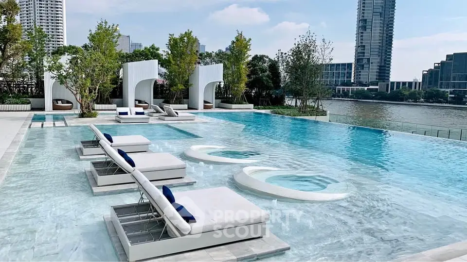 Luxurious riverside pool with modern lounge chairs and stunning cityscape view.
