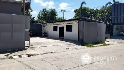 Industrial warehouse with metal siding and spacious outdoor area in urban setting.