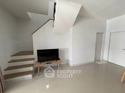 Modern minimalist living room with sleek staircase and TV setup