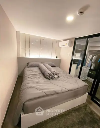 Modern bedroom with stylish decor and ample closet space, featuring a cozy bed and sleek lighting.
