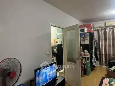 Cozy living room with TV, fan, and open door to kitchen area