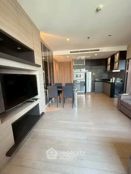 Modern open-plan living room with sleek kitchen and dining area, featuring hardwood floors and contemporary design.