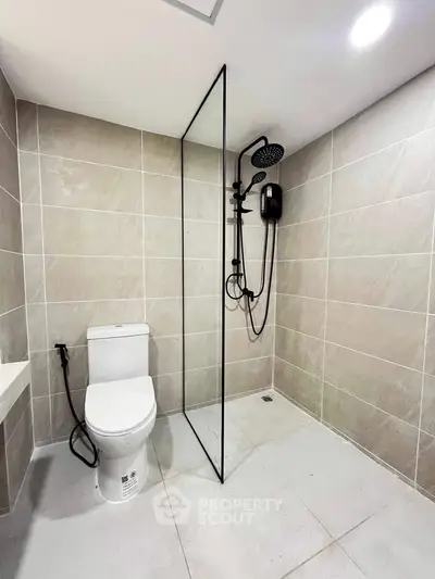 Modern bathroom with sleek shower and toilet in neutral tones.