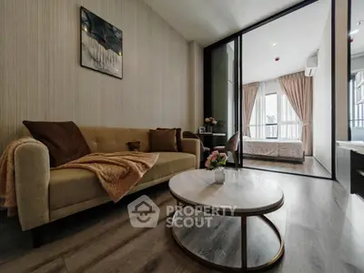 Modern living room with cozy sofa and stylish decor leading to a bright bedroom.