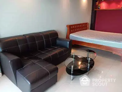 Modern studio apartment with stylish black leather sofa and elegant wooden bed.