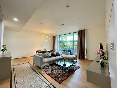 Spacious modern living room with elegant decor and large windows opening to a lush balcony view.