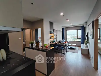 Modern open-plan living room with kitchen and city view, featuring stylish decor and ample natural light.