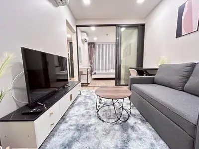 Modern living room with sleek furniture and open layout, featuring a cozy sofa and large TV.