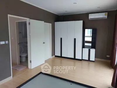 Spacious bedroom with modern wardrobe and air conditioning, featuring a glimpse of an ensuite bathroom.