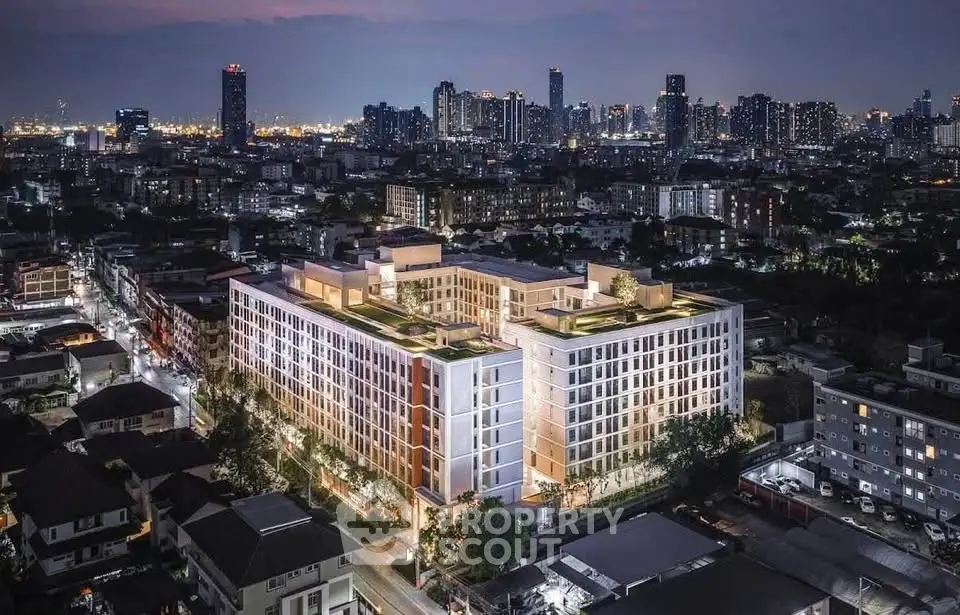 Stunning aerial view of modern apartment complex with city skyline at dusk, showcasing urban living.