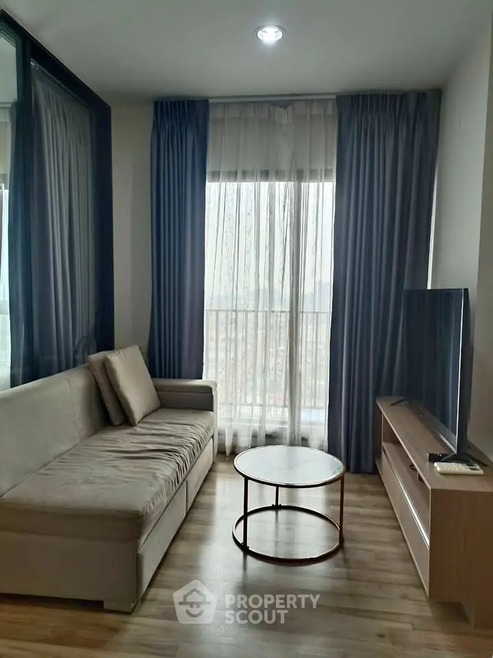 Cozy living room with modern sofa and large window offering natural light.