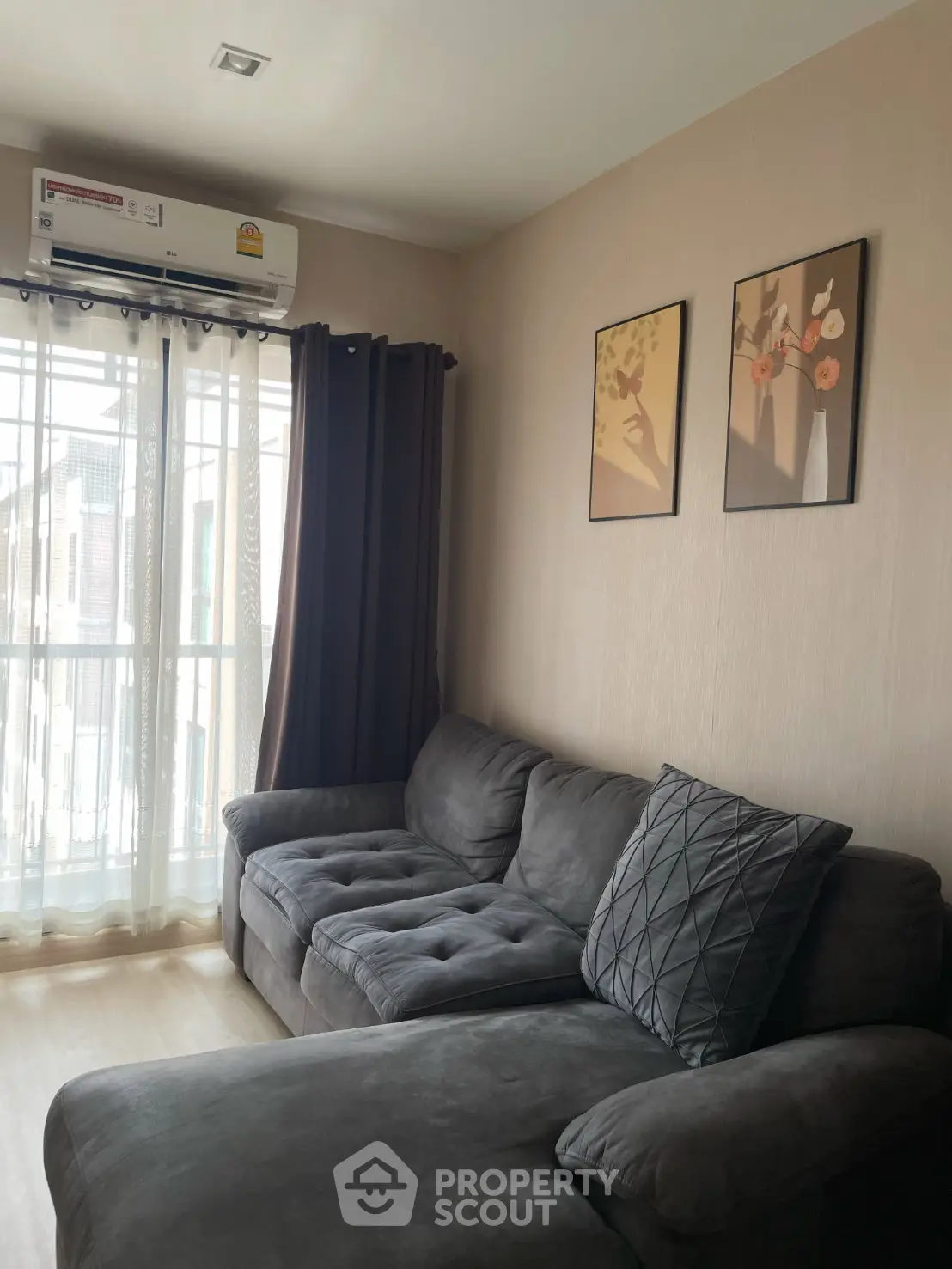 Cozy living room with plush gray sofa and wall art, featuring natural light from large window.
