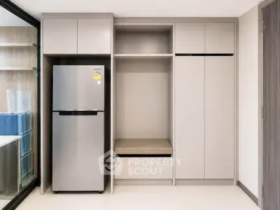 Modern kitchen with sleek cabinetry and stainless steel fridge in a stylish apartment.