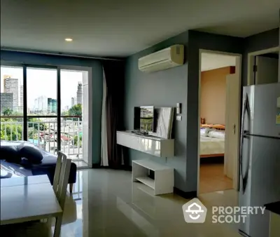 Modern apartment interior with city view, featuring open living space and balcony access.