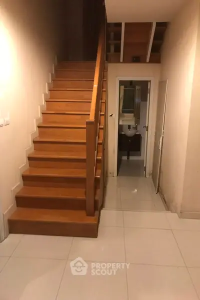 Spacious hallway with wooden staircase and modern bathroom entrance