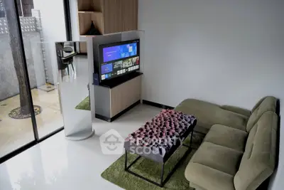 Modern living room with sleek TV setup and stylish furniture, featuring a unique coffee table and green accents.