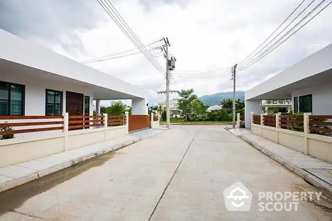 Modern residential street with contemporary homes and scenic mountain backdrop.