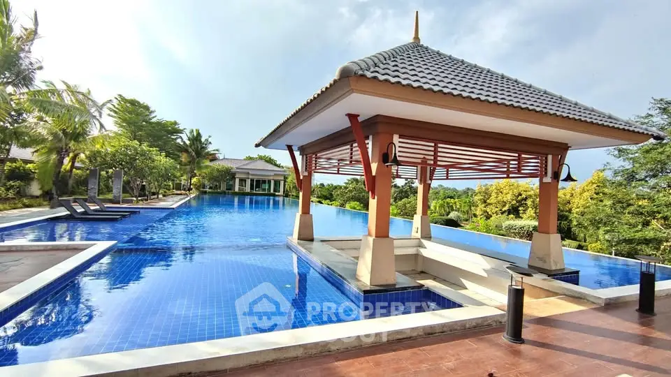 Luxurious resort-style pool with gazebo and lush greenery, perfect for relaxation and leisure.