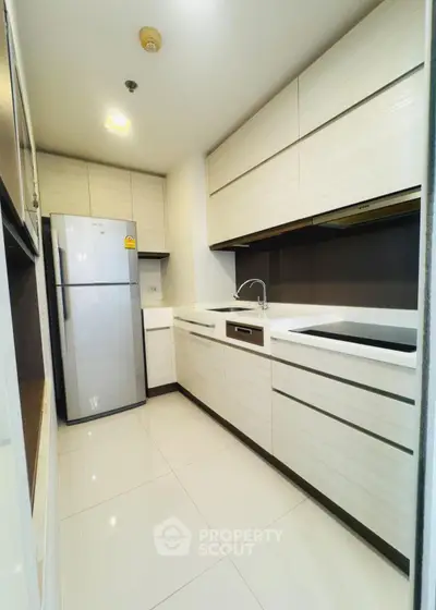 Modern kitchen with sleek cabinetry and stainless steel fridge in a compact layout.