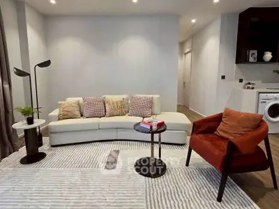 Modern living room with stylish furniture and washing machine in open layout.