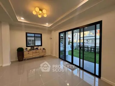Spacious living room with modern lighting and large sliding glass doors opening to a garden view.