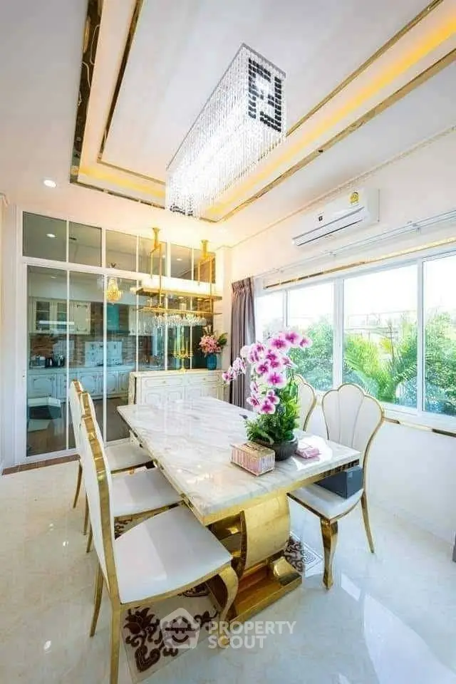 Luxurious dining room with elegant chandelier and marble table, featuring large windows and modern decor.