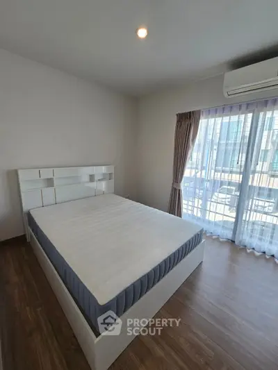 Spacious bedroom with large window and modern furnishings in a bright apartment.