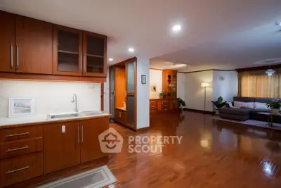 Spacious open-plan living room with wooden flooring and modern kitchen cabinetry.