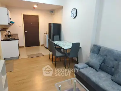 Modern open-plan living room with kitchen and dining area, featuring sleek furniture and wooden flooring.