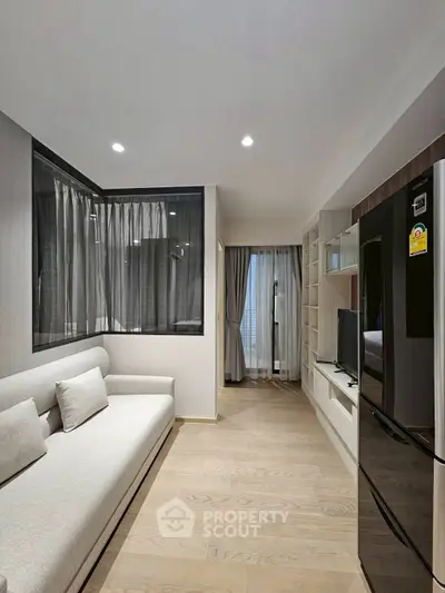 Modern living room with sleek design and large window, featuring a comfortable sofa and flat-screen TV.