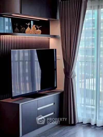 Modern living room with sleek TV setup and elegant curtains in a high-rise apartment.