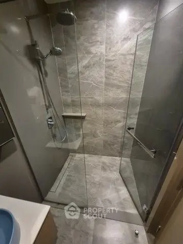 Modern bathroom with sleek glass shower enclosure and elegant marble tiles.