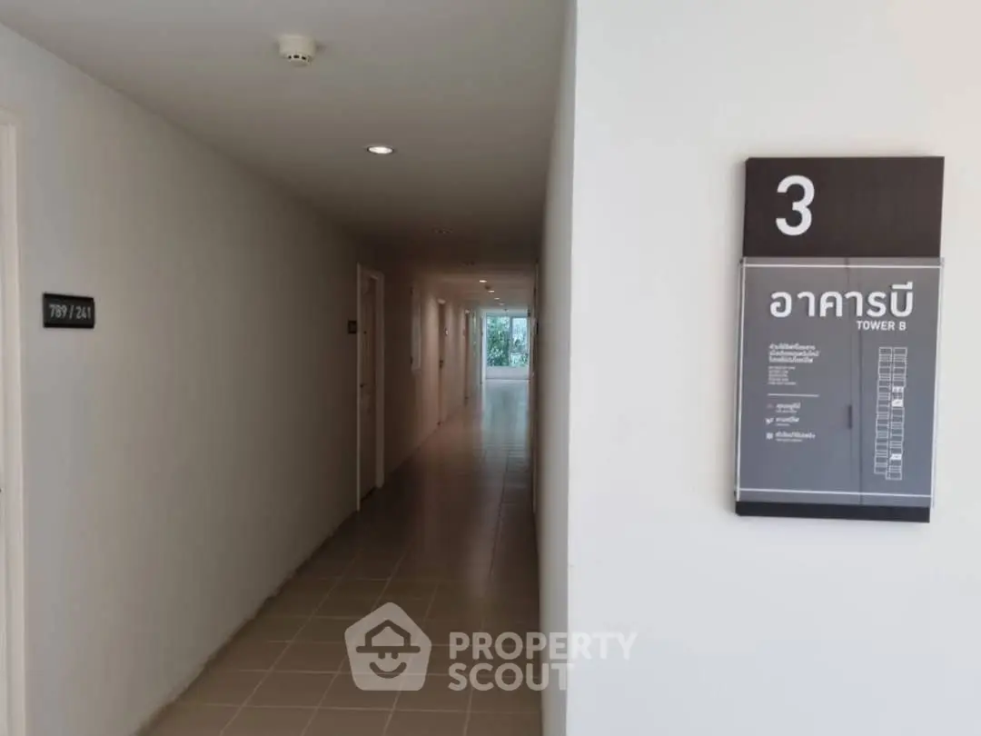 Modern apartment hallway with room numbers and building directory sign.