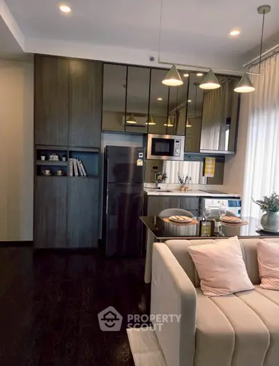 Modern kitchen with sleek appliances and cozy living area in open layout apartment.