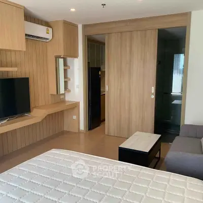 Modern bedroom with wooden accents and sliding door, featuring a cozy sofa and wall-mounted TV.