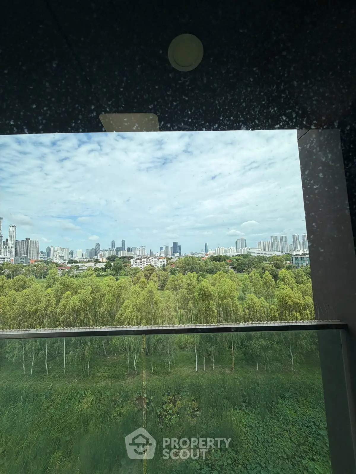 Stunning cityscape view from a high-rise balcony overlooking lush greenery and skyline.