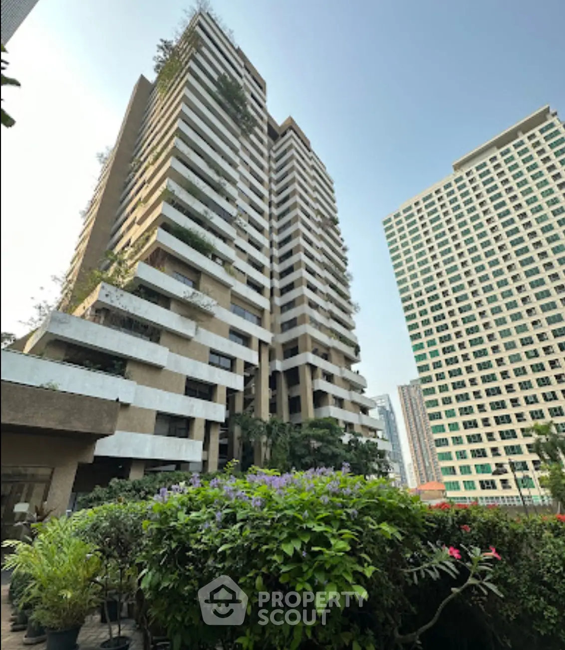 Stunning high-rise building with lush greenery and modern architecture in urban setting.