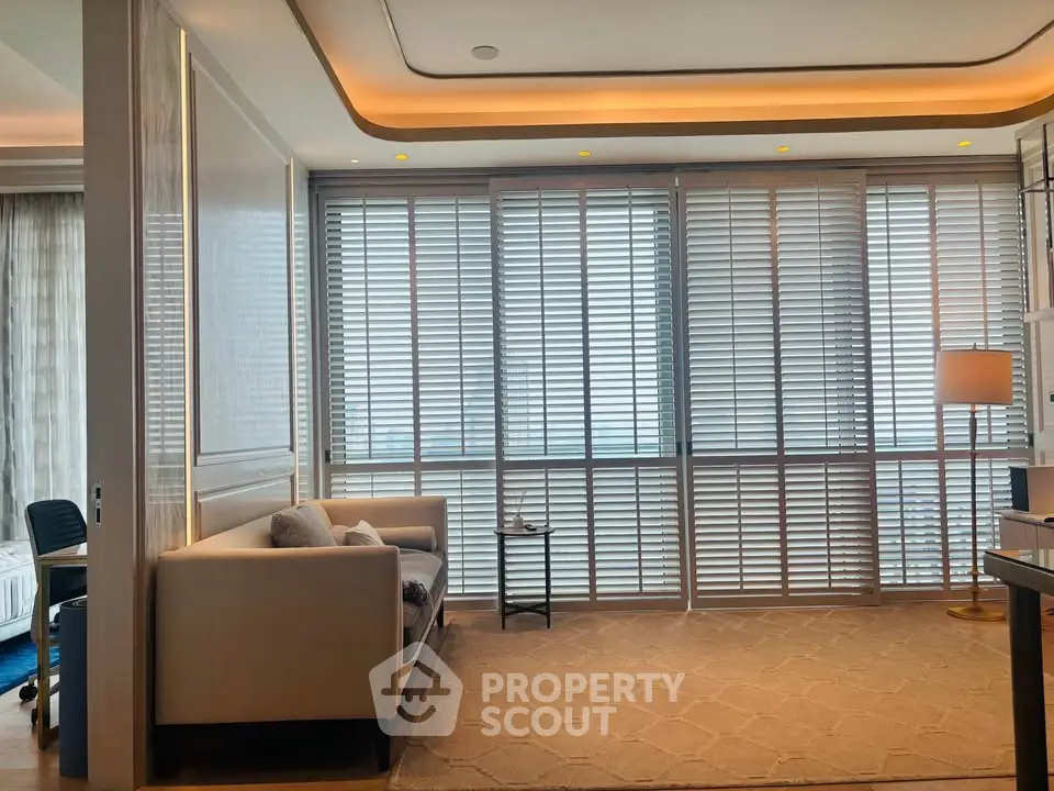 Luxurious living room with elegant sofa and floor-to-ceiling windows with blinds, perfect for relaxation.